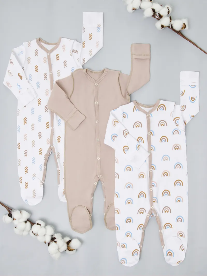 Tender baby sleepers flatlay - arrow print, solid beige, rainbow print with cotton branches decoration