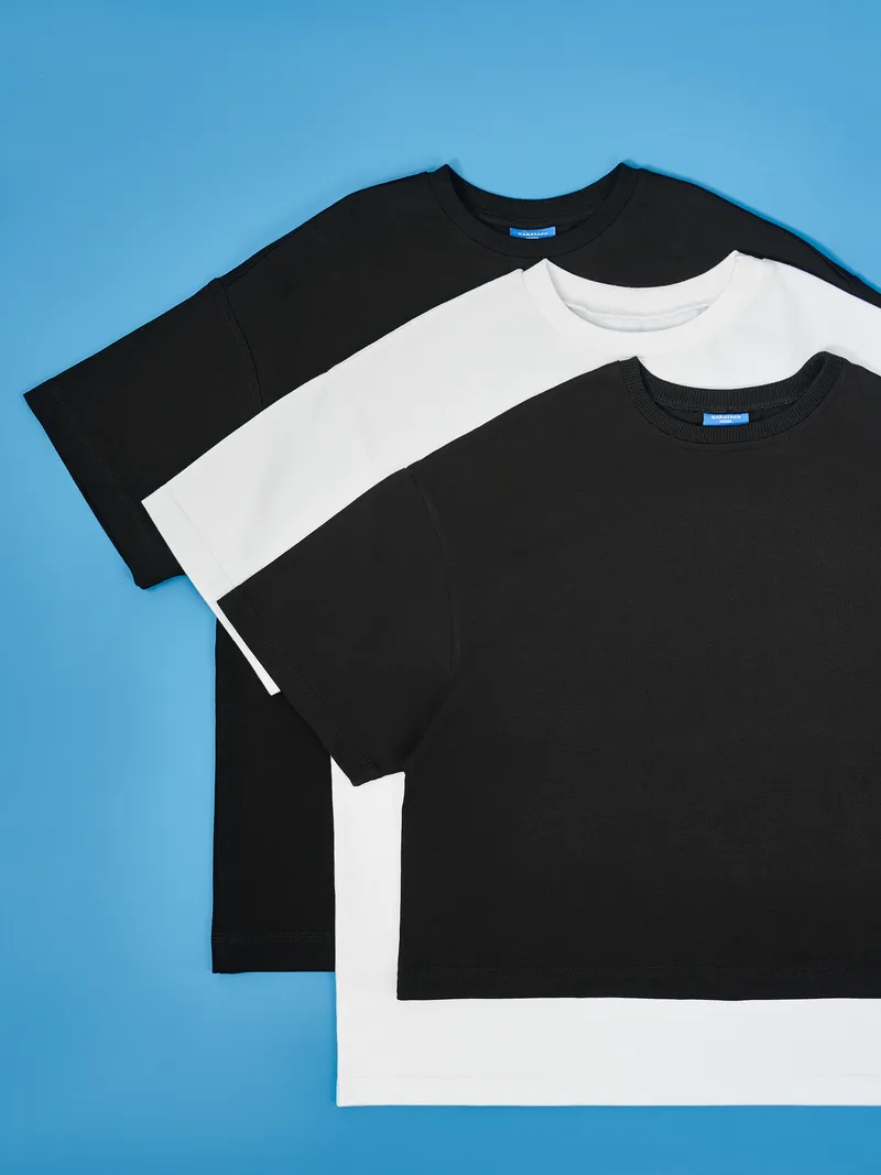 Стопка чёрно-белых футболок на ярко-синем фоне. Идеально для соцсетей!