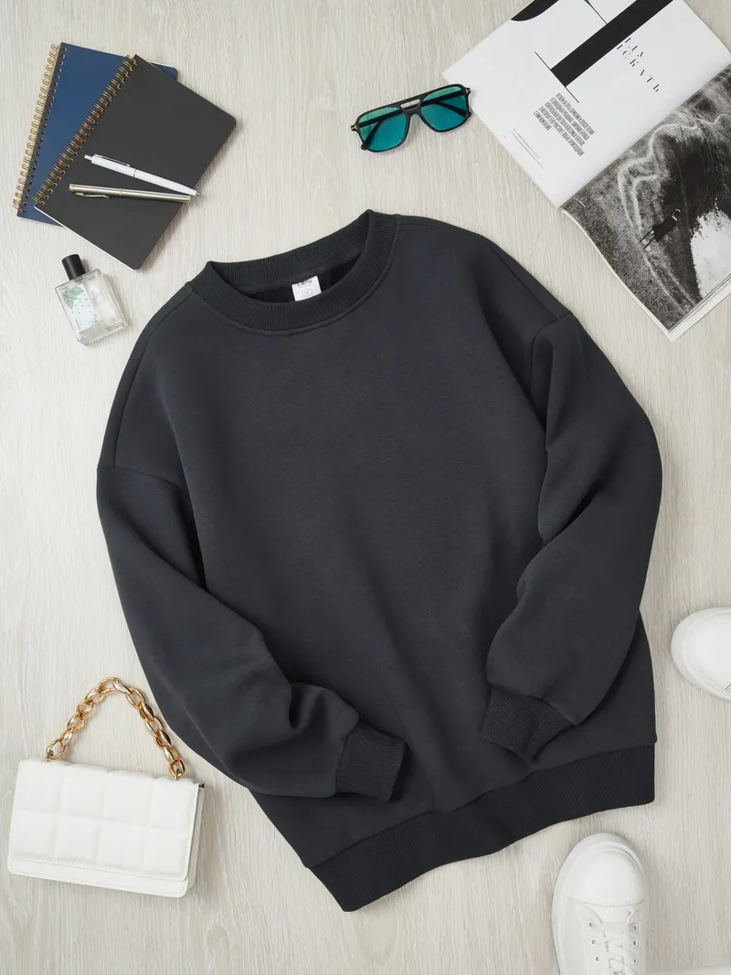 Dark charcoal sweatshirt with colorful accessories - teal sunglasses, white quilted bag with gold chain, blue notebooks